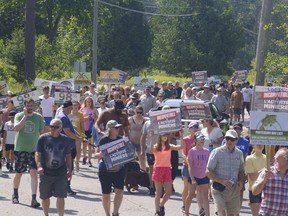 Protesters walk down a road holding signs about mining and its impact on the environment.