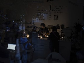 A barman is seen working through the window of a coffee shop during power cuts in Kyiv, Ukraine, Friday, June 7, 2024.