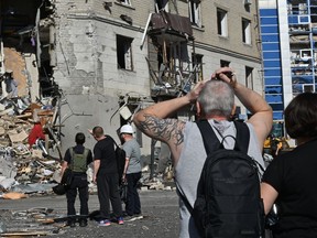 Local residents react near a residential building destroyed by an aerial bomb explosion in the centre of Kharkiv, on June 22, 2024, amid the Russian invasion of Ukraine.