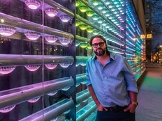 A man stands next to a colourful wall in a café.