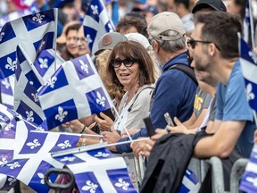A crowd of people hold Quebec flags as they watch the Fête nationale parade.