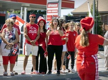 Onlookers in red and white cheer on a Canada Day parade.