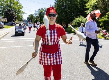 A juggler in red and white tosses pins in a Canada Day parade.