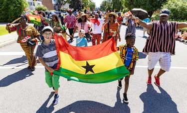Children hold the flag of Ghana while leading a group in a Canada Day parade.