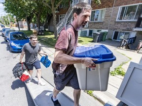 Two men carry items into a moving truck.