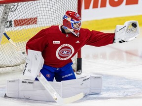 Jacob Fowler, wearing a red Canadiens practice jersey, makes a glove save in front of the goal