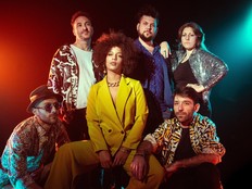 Six people pose for a photo in a dark room with colourful spotlights