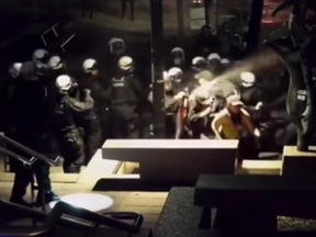 Riot police appear to spray a chemical irritant at a group of protesters at night