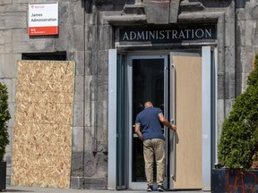 A man enters a partially boarded up doorway. A window to the left is also boarded up. A sign reading Administration is over the door.
