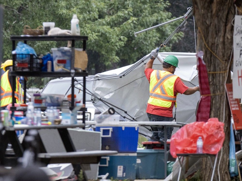 A worker removes tarp from a large tent.