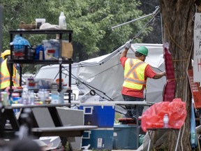 A worker removes tarp from a large tent.