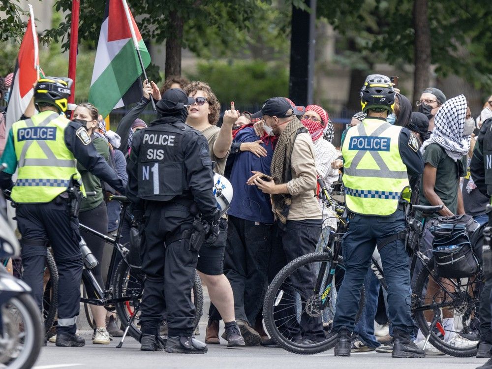 A woman in a crowd of protesters give police the finger.