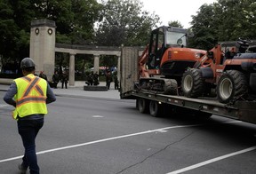 Excavators are on a flatbed truck in front of the Roddick Gates.