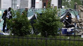 Security guards and crew are seen near stripped tents and pallets.