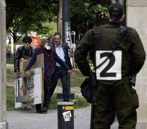 A protester removes large wooden signs under the watch of a police officer.
