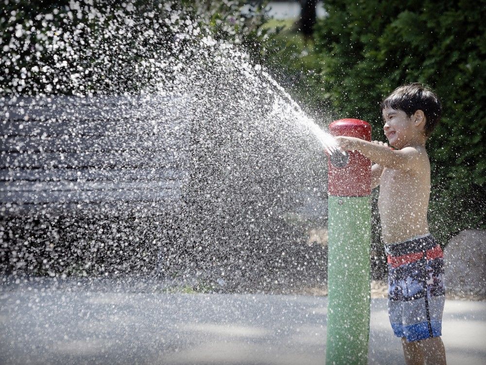 A young boy plays with a sprinkler at a trash pad