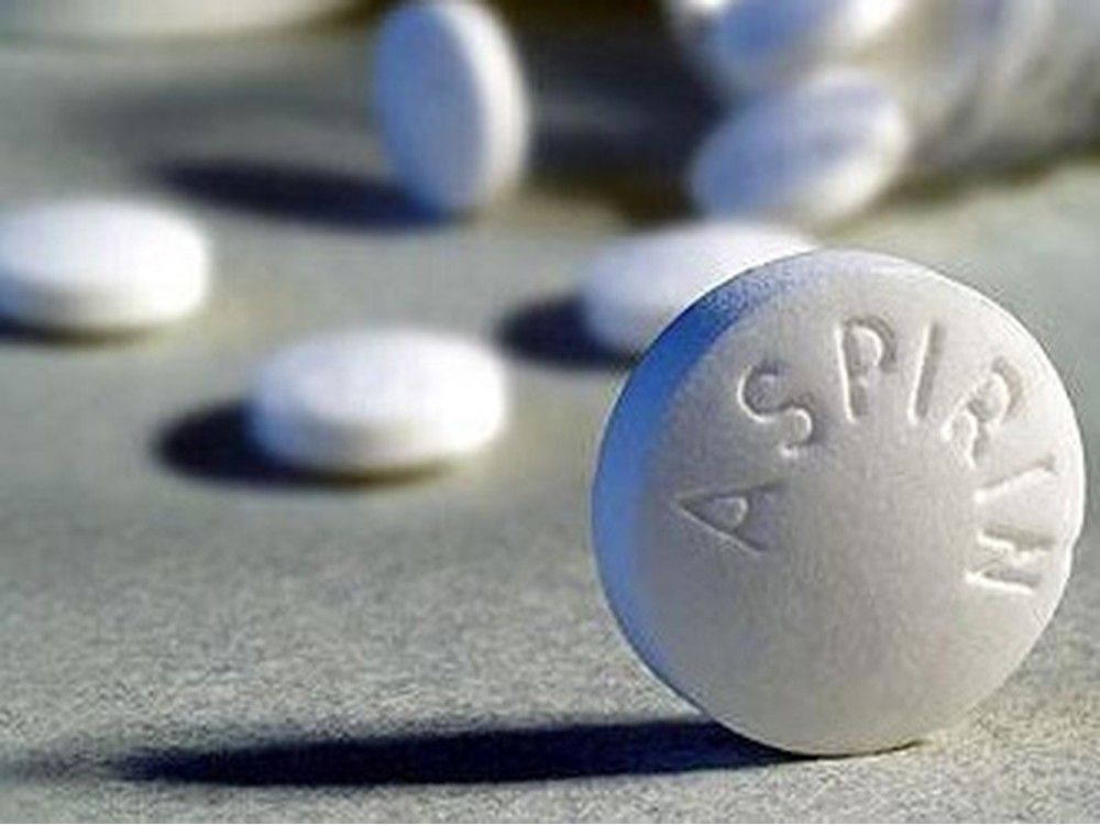 A closeup of an upright Aspirin tablet with other tablets in the background.
