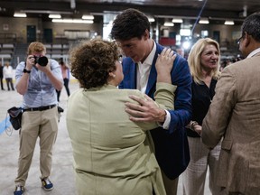 Justin Trudeau holds a woman's shoulders and brings his head close to hers while a photographer takes a photo