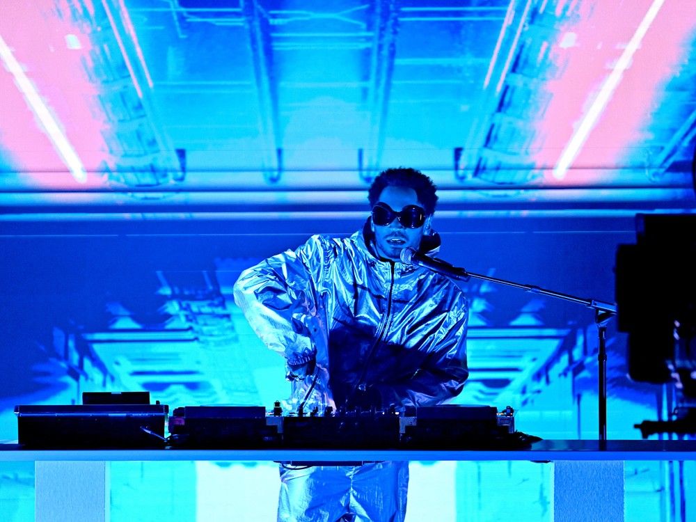 Kaytranada, bathed in blue light, behind the DJ decks during a performance