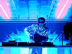 Kaytranada, bathed in blue light, behind the DJ decks during a performance