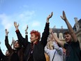 Young people raise their hands in celebration of the left-wing coalition's projected victory in France's parliamentary elections