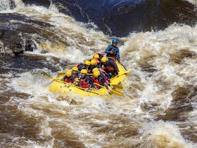 Several people in a large yellow raft ride through rapids.
