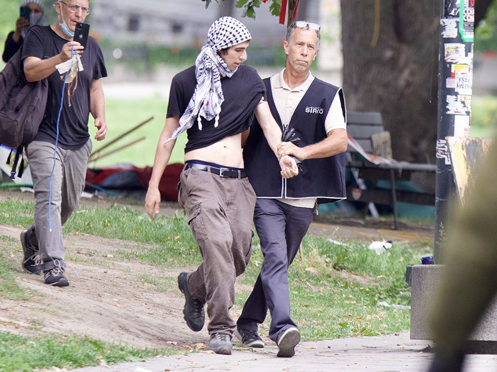 A man escorts a protester. Another man follows, recording with his phone.