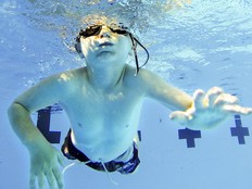 A boy with goggles swims in a pool.
