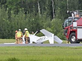 A small Cessna plane lies on its back while firefighters tend to it next to a runway