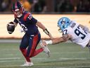 Alouettes quarterback Davis Alexander eludes pressure by Argonauts lineman Derek Parish during pre-season action.