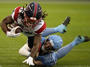 Alouettes wide receiver James Letcher Jr. is seen reaching forward with the ball in his right arm while being tackled by Argonauts linebacker Fraser Sopik.