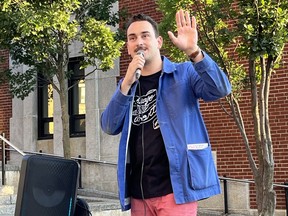 A man speaks into a microphone outside a building