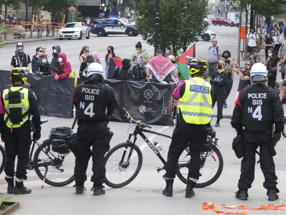 A line of police watch pro-Palestinian protesters on a city street.