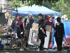 Protesters remove belongings and signs at a tent city.