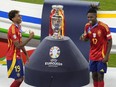 Young Spanish stars Lamine Yamal, left, and Nico Williams are seen flanking the Euro 2024 trophy, which Spain won on Sunday.