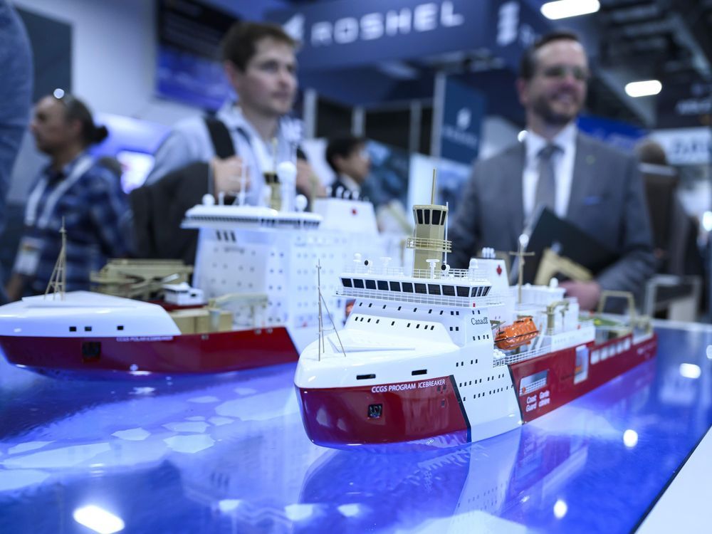 Men stand behind model ships