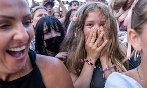 Two girls in a crowd are smiling.