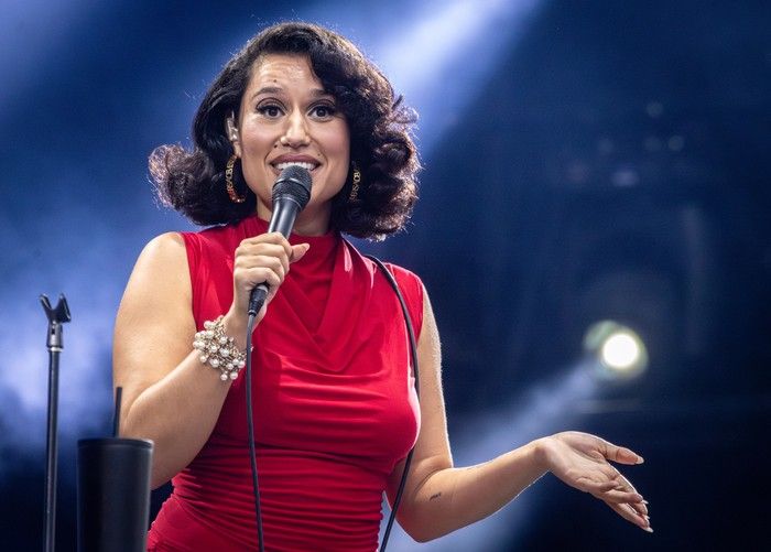 Ray sings into a microphone on stage