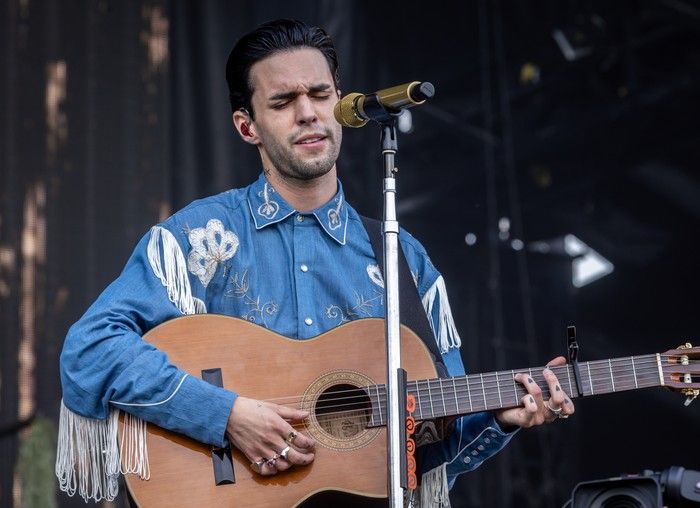A man strums an acoustic guitar as he sings into a microphone