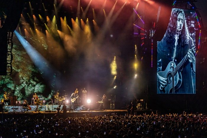 Hozier is seen on the big screen next to the stage as he performs at an outdoor festival