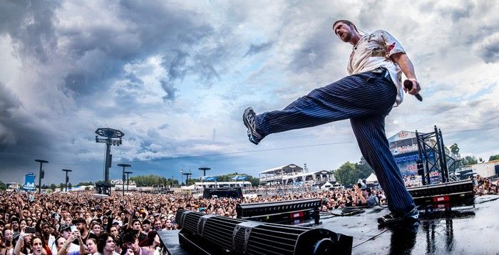 Low-angle shot of a man kicking his leg as he performs on stage at a music festival