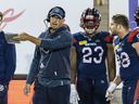 Alouettes head coach Jason Maas speaks with defensive-tackle Dylan Wynn, right, as defensive-end Ellis Avery, No. 23, listens during game against the Lions at Molson Stadium this month.