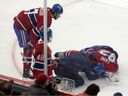 Concerned Canadiens teammates Josh Anderson, left, and Lane Hutson look on as a trainer attends to Patrik Laine after the forward was injured in a knee-on-knee collision against the Maple Leafs during pre-season action on Saturday night at the Bell Centre.