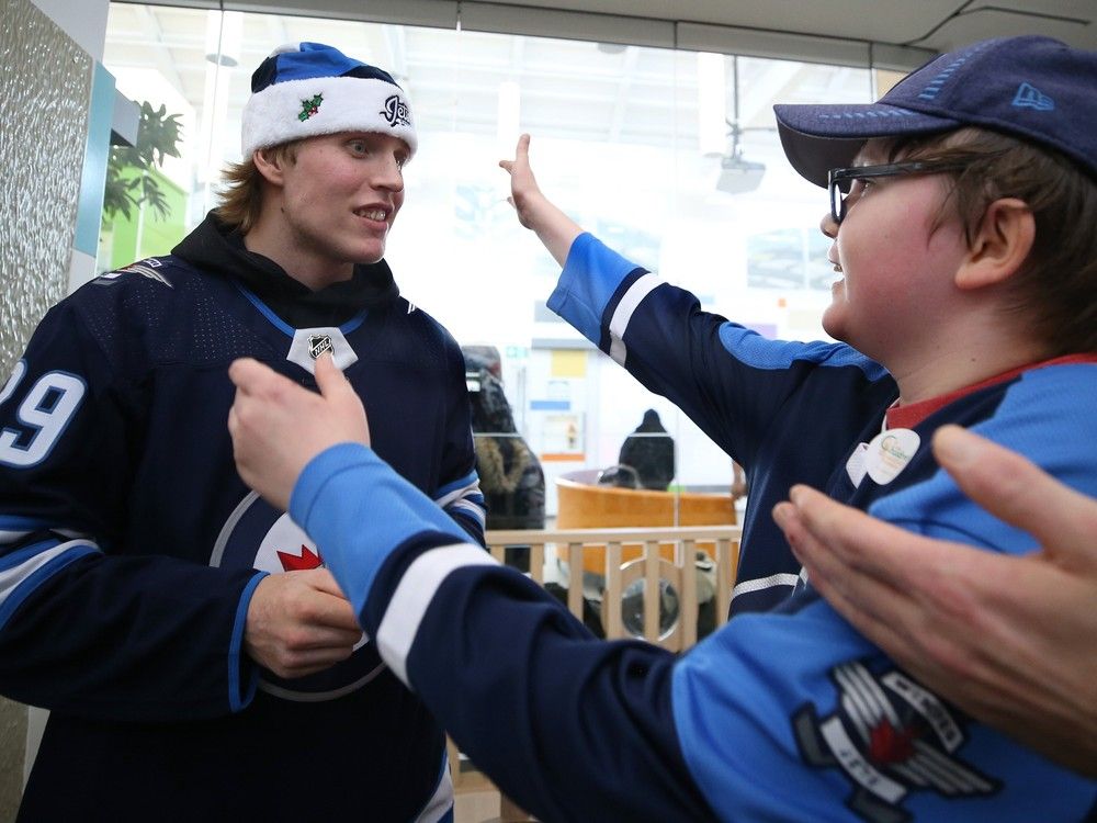 Patrik Laine moves in to give a hug to young fan Adam Martin, 16, during the Winnipeg Jets' annual holiday hospital visit in 2019.