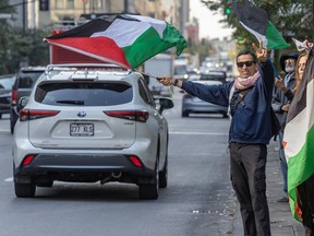 A man waves Palestinian flag at passing cars on Sherbrooke St.