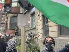 A masked person smashes windows at McGill on Monday, Oct. 7, 2024.