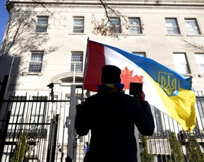 A man with Canadian and Ukrainian flags is seen from behind.
