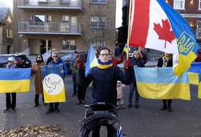 Montreal city councillor Serge Sasseville holds a Canadian flag as he stands between a baby stroller and a row of protesters with the Ukrainian flag.