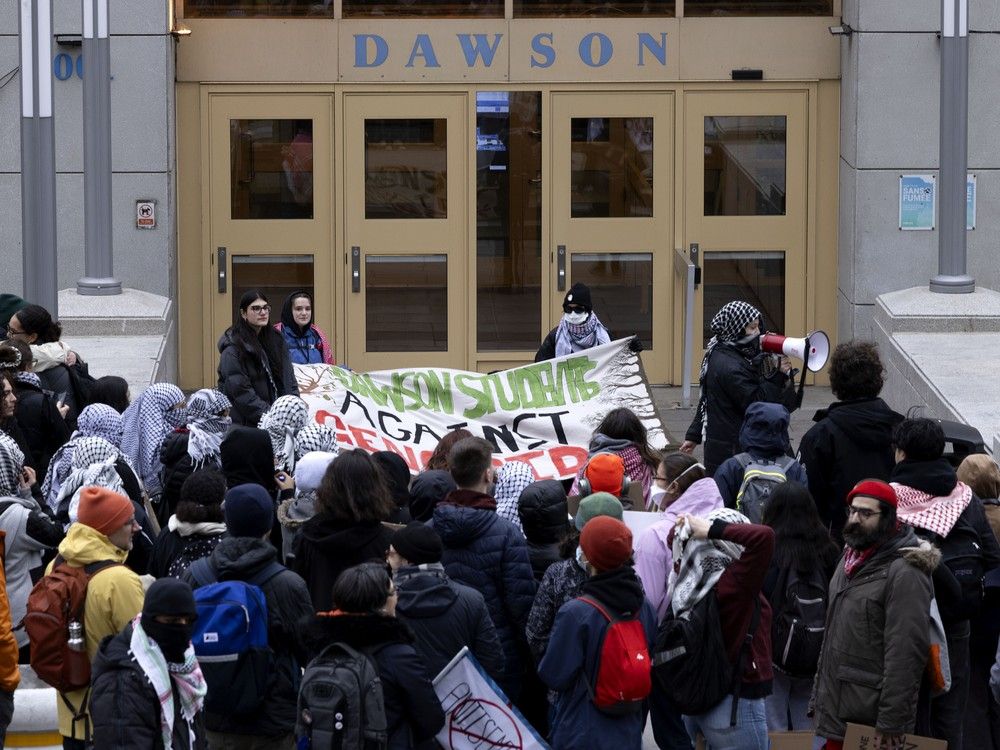 a building entrance with the word dawson above it with a small group of protesters in front