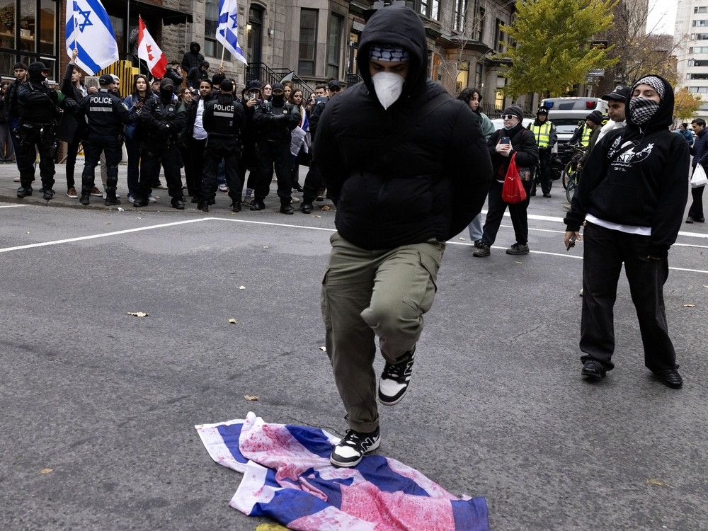 A man dances on the Israeli flag as students gather outside Concordia University to protest against the continuing conflict in Gaza. The students are seen in Montreal on Thursday, Nov. 21, 2024.
